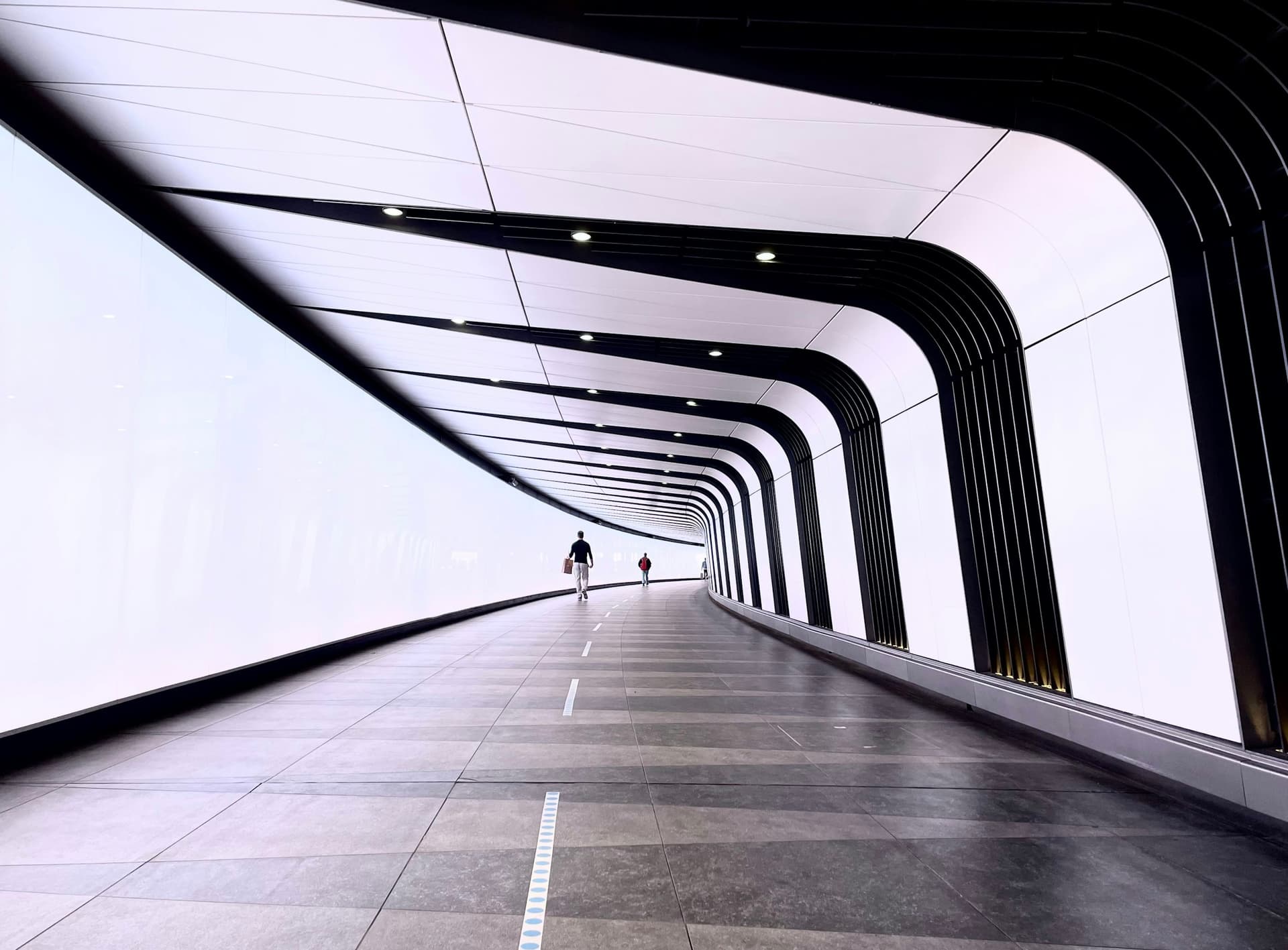 A long white pedestrian tunnel in London, its ribbed lighting running to a point.